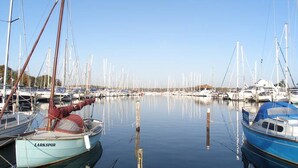 Un port de plaisance où sont amarrés de nombreux bateaux, l’eau est calme et le ciel est dégagé.