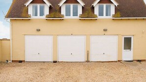 Un bâtiment à deux étages, doté d’un toit à pignon, de trois portes de garage et d’une petite porte d’entrée.