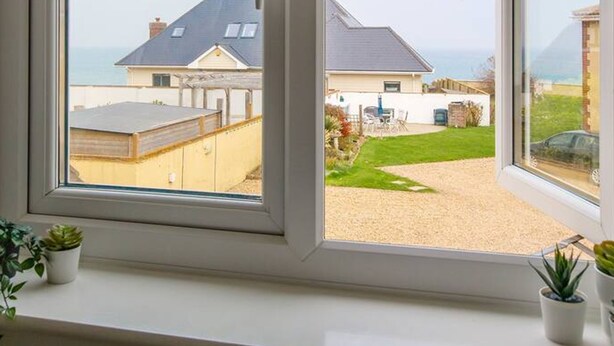 Une fenêtre donnant sur un quartier résidentiel, avec des maisons et une cour verdoyante.
