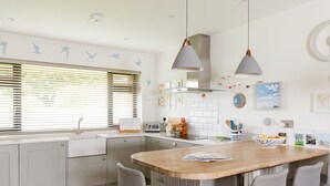 Une cuisine moderne dotée d’un îlot central, de tabourets de bar et de luminaires suspendus.