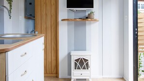 A modern kitchen with a wooden cabinet, a built-in sink, a white stove, and a mounted TV.