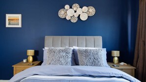A bedroom with a bed, two nightstands, a wall art piece, and a framed picture. - Newly Refurbished Seaside Escape - 5 Mins to Beach (Chichester)