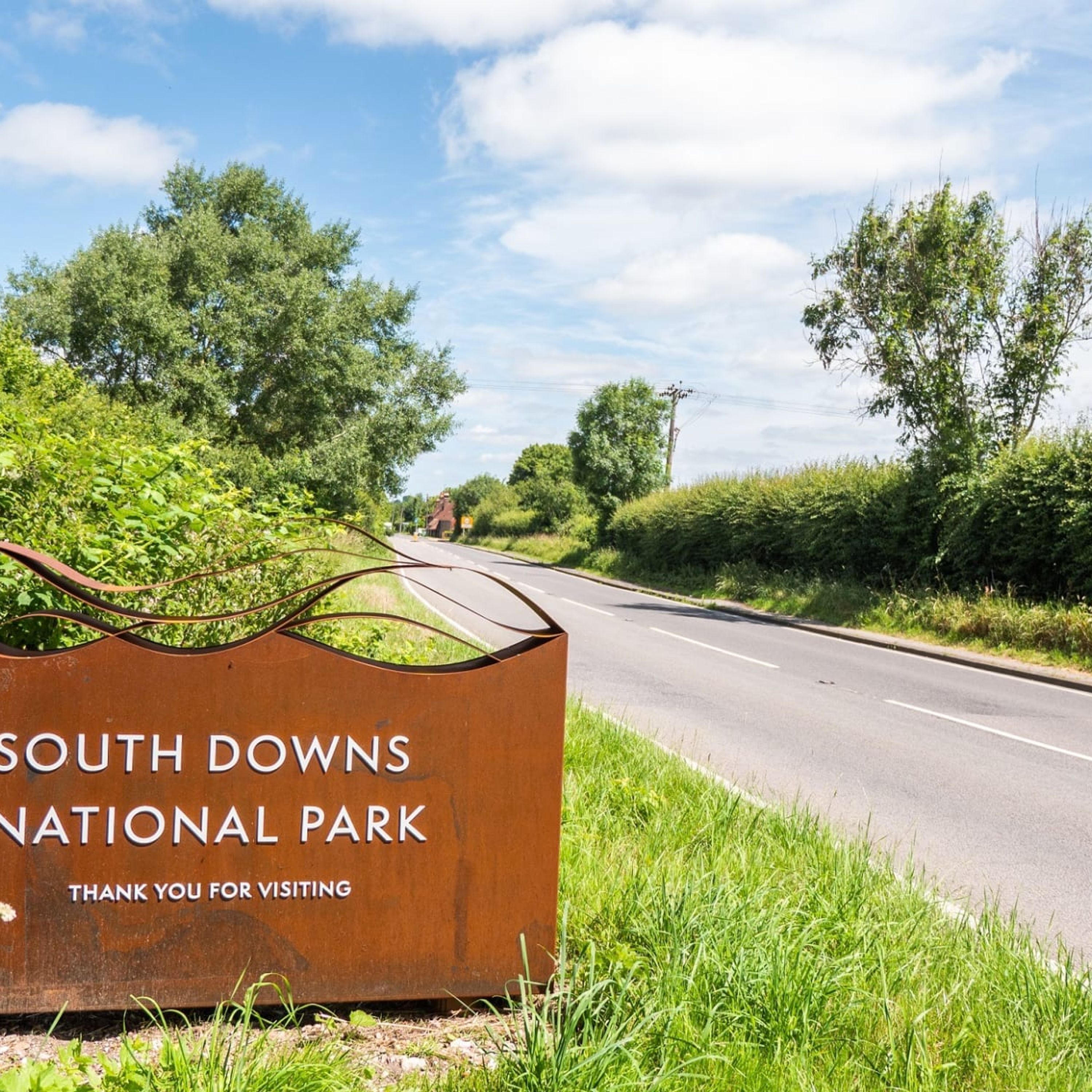Un letrero del Parque Nacional South Downs, con una carretera al fondo.