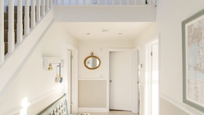 Un hall d’entrée spacieux, avec un banc en bois, un escalier et une porte donnant sur une autre pièce.
