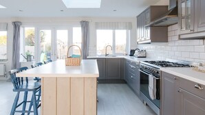 Une cuisine moderne dotée d’un îlot central, de meubles de couleur grise et d’une grande fenêtre qui laisse entrer la lumière naturelle.