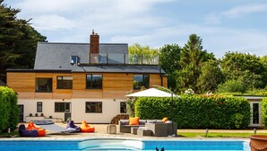 A modern house with a swimming pool, outdoor seating, and a garden. - Stunning 5BR Home With Pool - 5 min to Beach (Chichester)