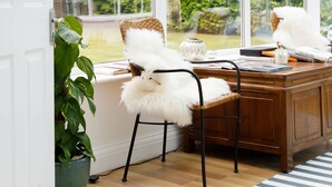 A conservatory with a wooden desk, white chairs, and a potted plant. - Stunning 5BR Home With Pool - 5 min to Beach (Chichester)