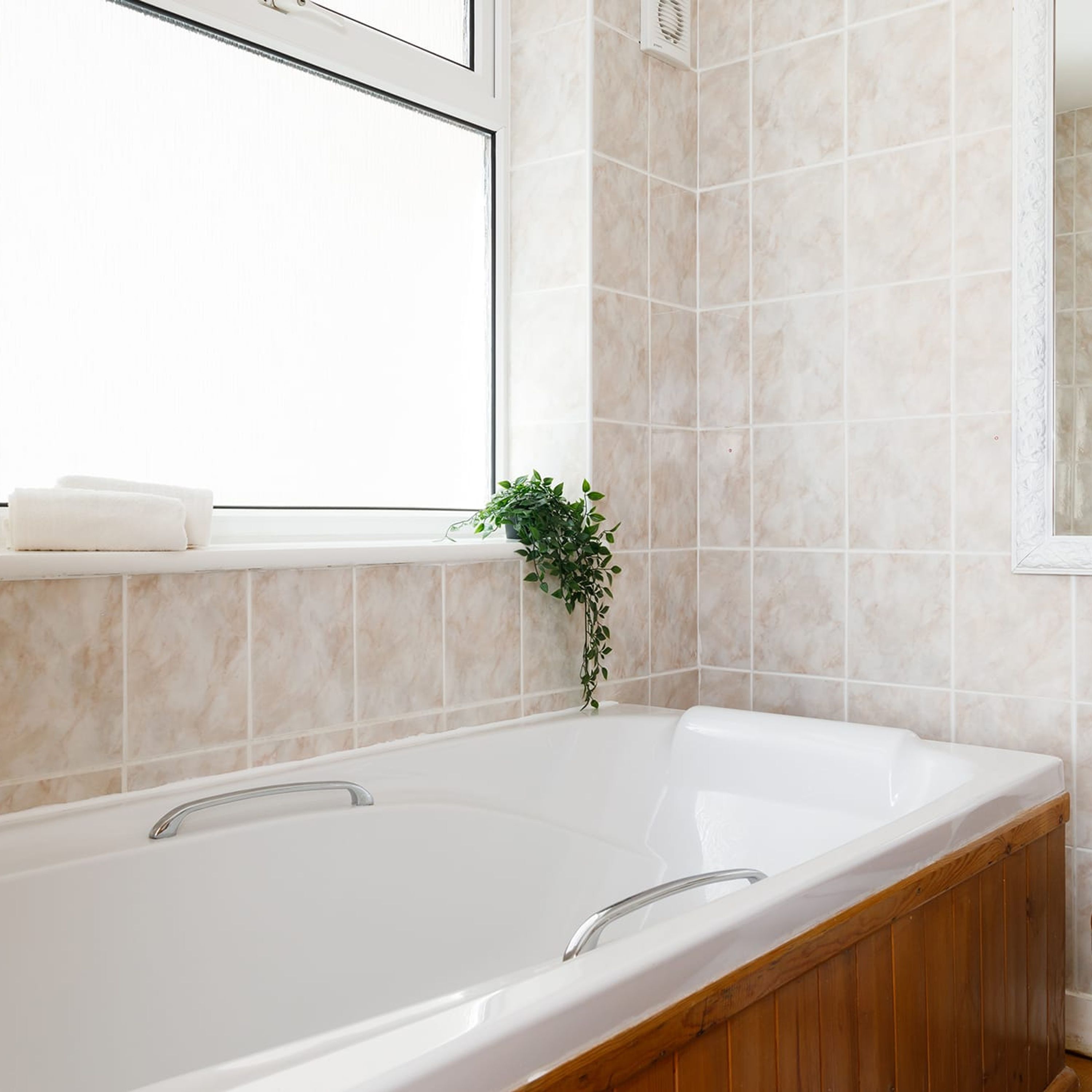 Ein modernes Badezimmer mit freistehender Badewanne, einem Fenster und einem Blumentopf.