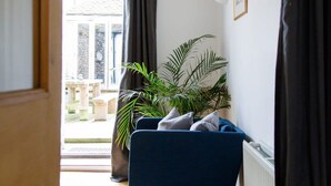 A narrow hallway with a wooden beam ceiling, a dark blue chair, a potted plant, and a radiator on the wall. - Charming 3bd Townhouse Right in the City Centre (Chichester)