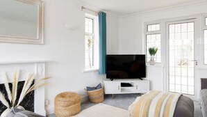 A living room with a sofa, a television, and a fireplace. - Bright Modern 4 br House 100 Metres From Beach (Chichester)