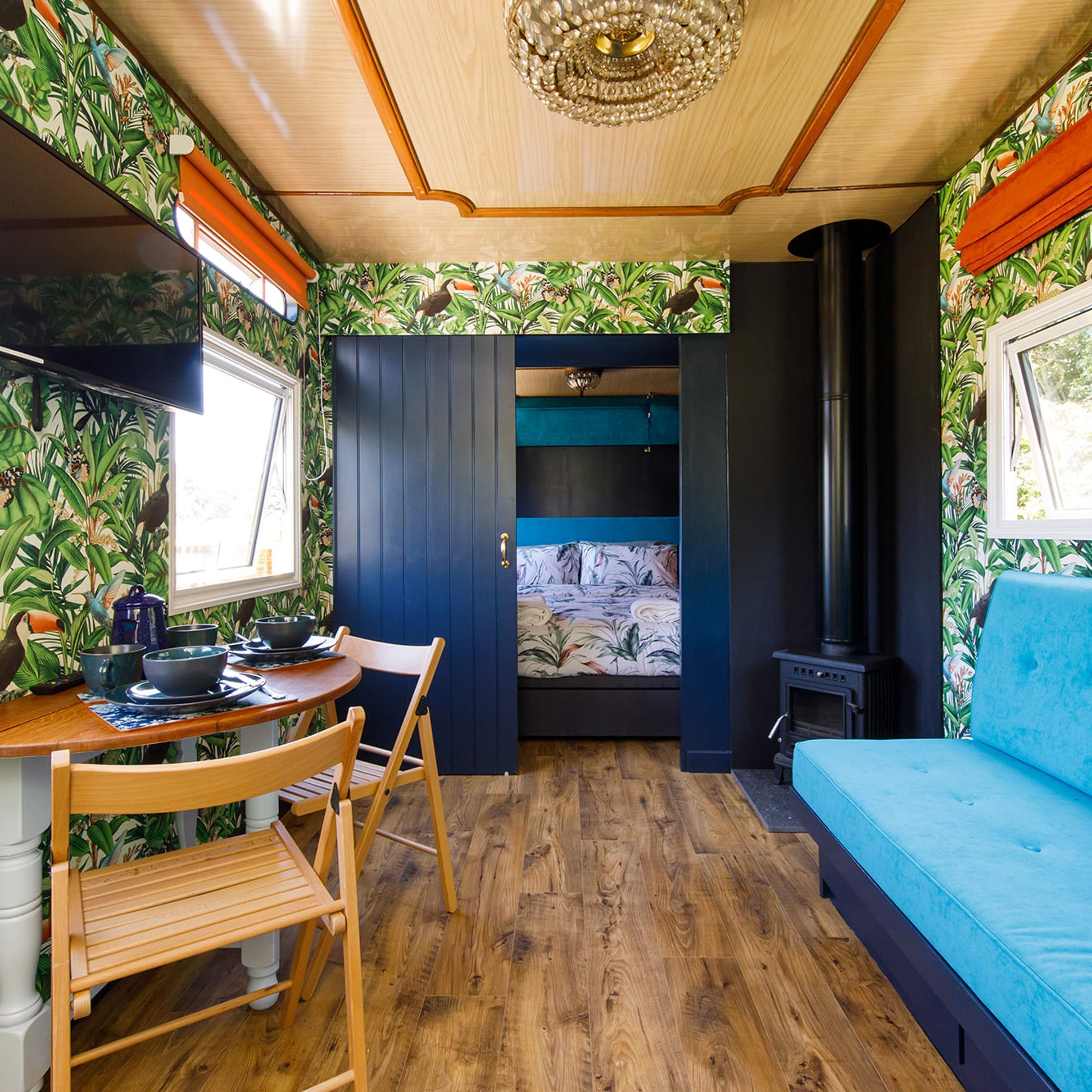 A compact room with a wooden dining table, a blue sofa, and a small TV.