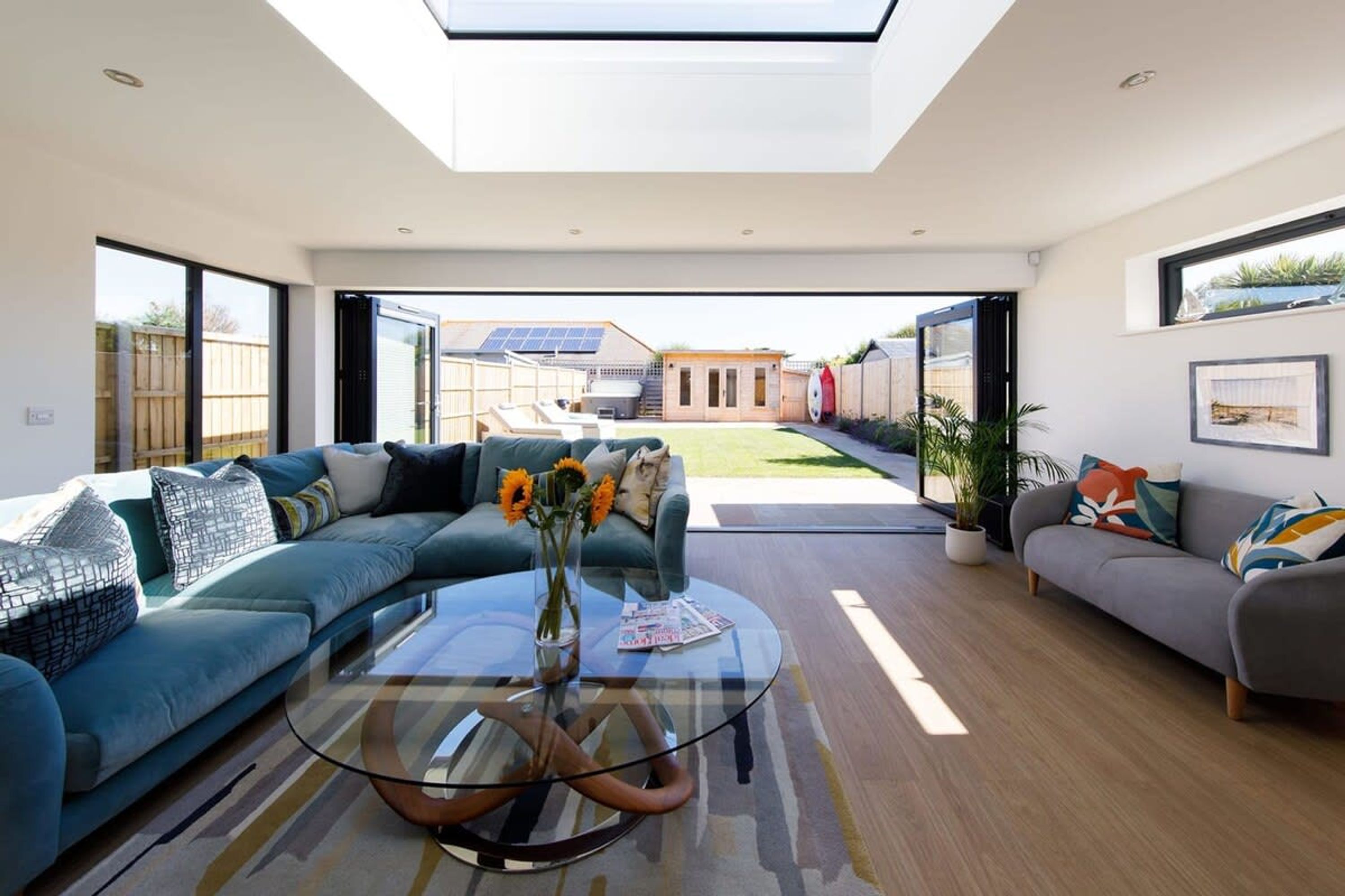 A modern living room with a glass coffee table, a sectional sofa, and a grey sofa.