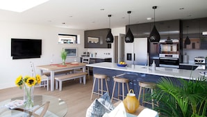 Cozinha moderna com uma ilha grande, banquetas e iluminação pendente.
