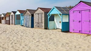 Une rangée de cabanes de plage, avec une plage de sable au premier plan.
