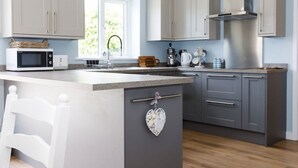 Une cuisine moderne avec des meubles gris, un îlot central blanc et un plancher en bois.
