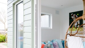 A modern interior with a large window, a wicker chair, and a sectional sofa with multiple cushions. - Amazing 5 BR Country Home Pool Gym Yoga Studio (Chichester)