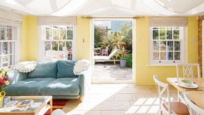 A bright, sunlit room with a blue sofa, a dining table with chairs, and a ceiling fan. - Amazing 5 BR Country Home Pool Gym Yoga Studio (Chichester)