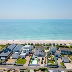 Un quartier résidentiel situé sur la côte, avec des maisons, une piscine et une plage en arrière-plan.