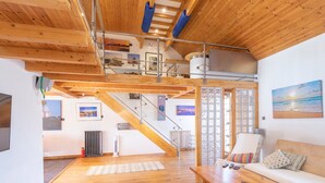 A spacious living area with wooden flooring, a sofa, a coffee table, and a staircase leading to an upper level. - Stylist Split Level 2 Bed With Parking (Chichester)