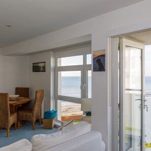 Ein Zimmer mit Essbereich, einem Bett und Blick aufs Meer.