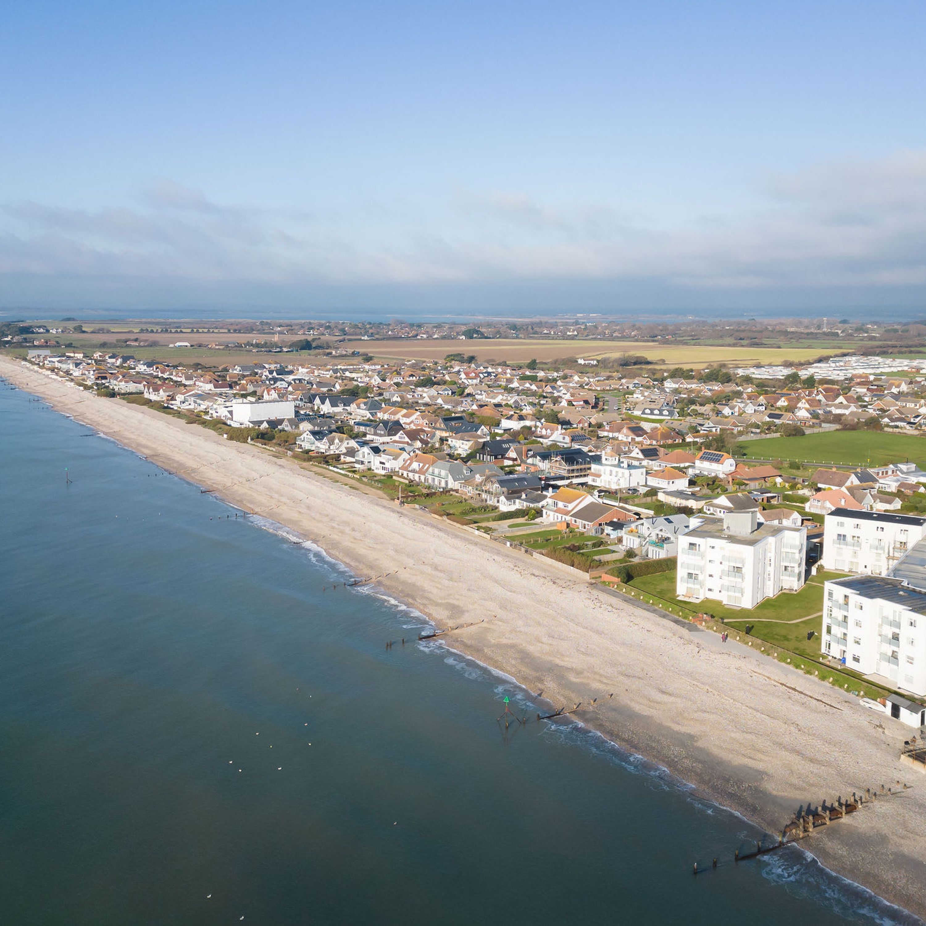 Een kustgebied met huizen aan het strand en een groot complex gebouwen in het binnenland.