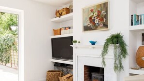 A living room with a fireplace, television, and bookshelves. - 3bd Family Beach Retreat in West Wittering (Chichester)