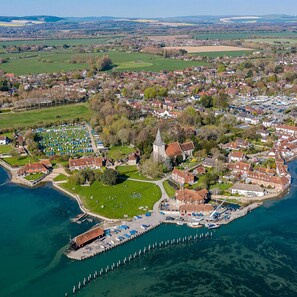 An aerial view of a coastal town with a marina, residential areas, and a church.