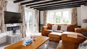 A living room with a leather sofa, a flat-screen TV, and a wooden coffee table. - Tranquil Luxe in Country Cottage (Chichester)