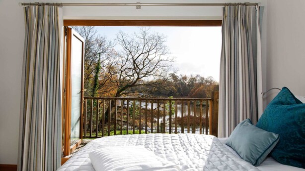 A hotel room with a large bed, a view of trees and a balcony. - Serene Riverside 6BR Luxury Retreat in Curdridge (Southampton)