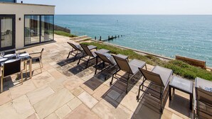 Eine Terrasse mit Lounge-Möbeln und einem Tisch mit Blick aufs Meer.