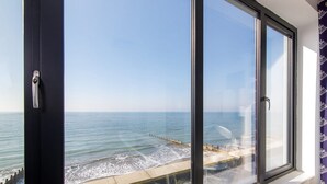 Ein Zimmer mit großen Fenstern und Meerblick, ein kleiner Tisch und ein Stuhl.