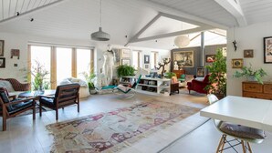 A spacious living room with a high ceiling, a large rug, and a variety of seating options including a sofa and chairs. - Luxury Countryside Haven for 10 (Chichester)