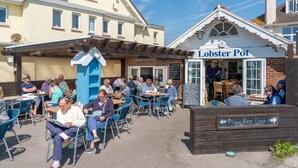 An outdoor seating area with tables and chairs, a small building labeled 'Lobster Pot', and a sign indicating 'Please Keep Clear'. - Chic 2-bed Seafront Haven Near Felpham Beach (Bognor Regis)