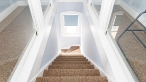 A carpeted staircase with a handrail, leading to a landing with a window. - Chic 2-bed Seafront Haven Near Felpham Beach (Bognor Regis)