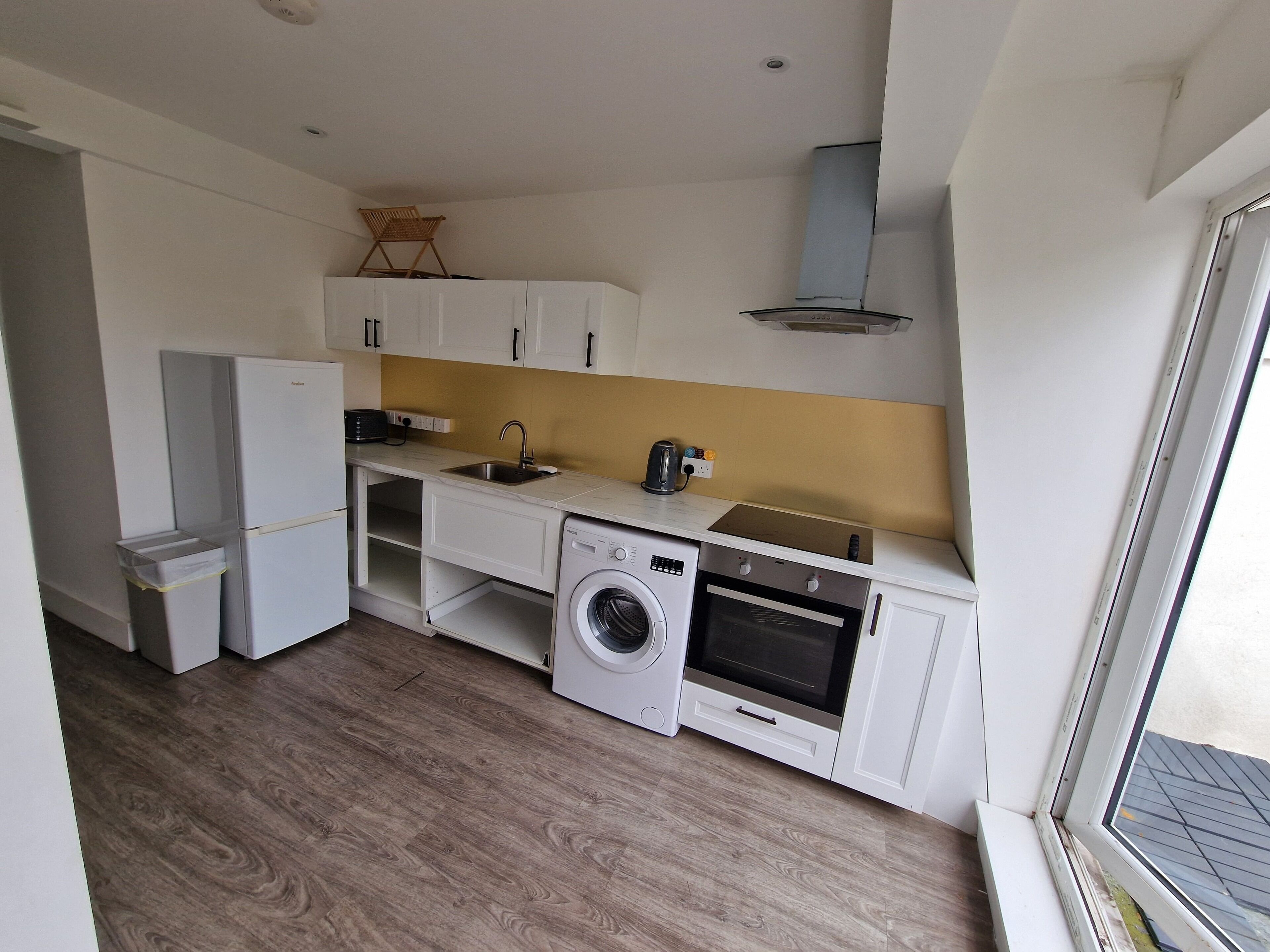 Een kleine keuken met een wasmachine, oven en gootsteen.