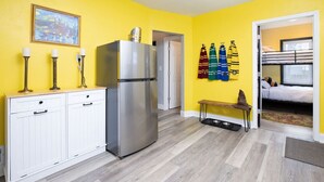 A compact kitchen with a refrigerator, white cabinets, and a bench. - Whimsical Magic Renovated Home - Walk to Downtown from Atlantic St. (Appleton)