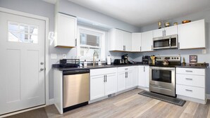 A modern kitchen with white cabinets, stainless steel appliances, and a black countertop. - Whimsical Magic Renovated Home - Walk to Downtown from Atlantic St. (Appleton)