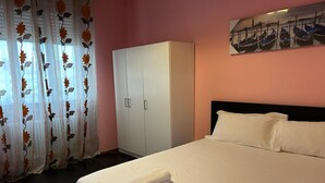 Una habitación de hotel con cama, armario y un cuadro en la pared.