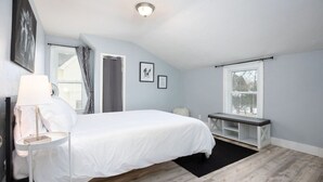 Une chambre à coucher avec un lit, une table de chevet, une lampe et une fenêtre avec des stores.