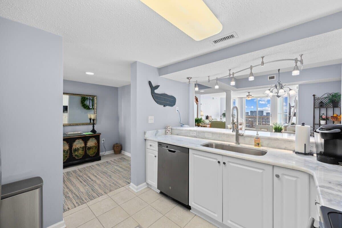 A modern kitchen with white cabinets, a dishwasher, a large island with a sink, and a whale decoration on the wall.