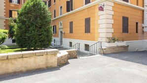 Un edificio de varios pisos con fachada de piedra, una escalera que lleva a la entrada y un cartel que indica una farmacia.