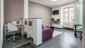Una sala de estar moderna con un escritorio blanco, un sofá púrpura y una mesa de comedor.