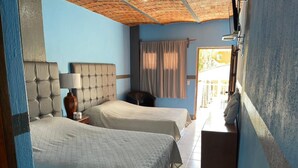 Una camera d'albergo con due letti, un comodino, una lampada e una finestra con tende.