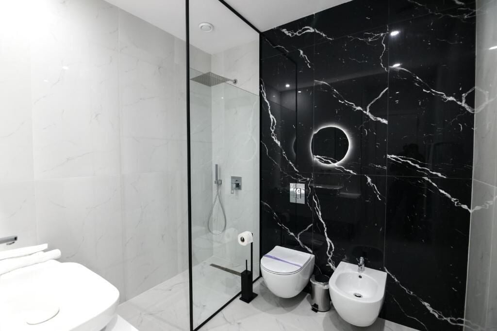 A modern bathroom with a glass-enclosed shower, a toilet, and a bidet.