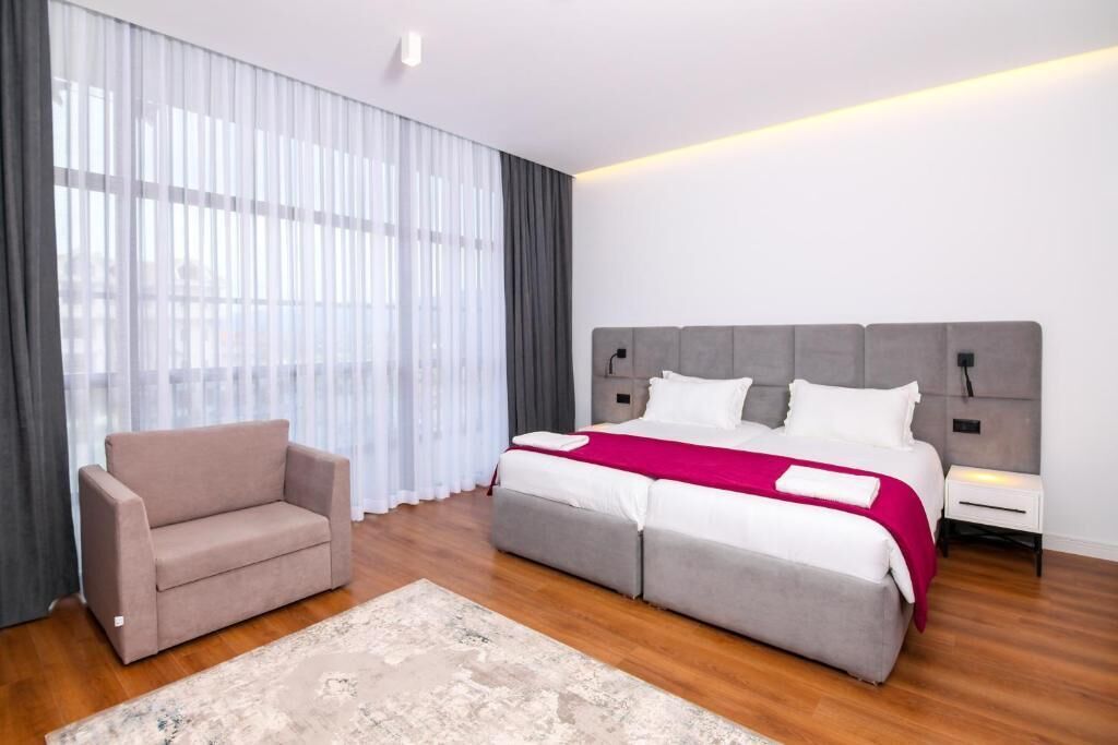 A modern hotel room with a large bed, a sofa, and a nightstand.