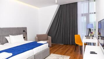 Una habitación de hotel moderna con cama, escritorio, silla y televisor.