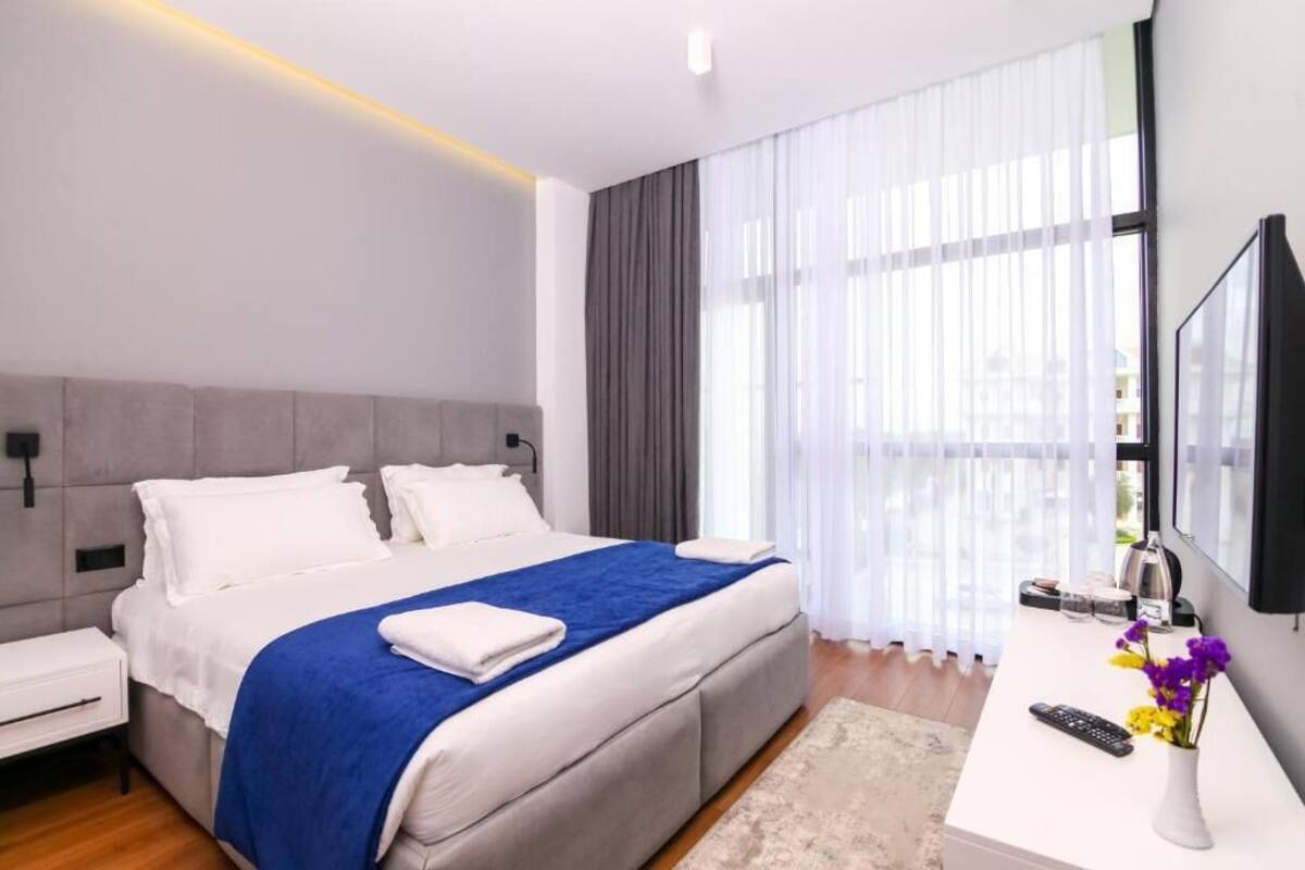 A modern hotel room with a large bed, a desk, and a TV.