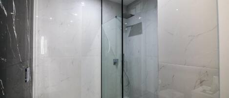 Un baño moderno con ducha envuelta en vidrio, inodoro y suelo de mármol.