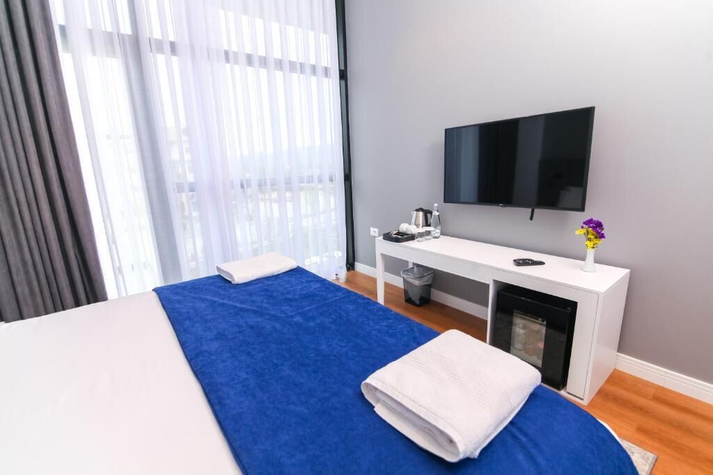 Une chambre d’hôtel équipée d’un lit, d’une télévision, d’une petite table avec une bouilloire et d’une poubelle.