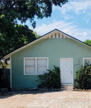 A single-story building with a green exterior, a white door, and a garage door.